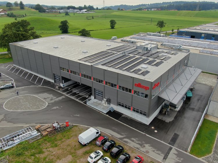 Das Allcop Firmengebäude in Lindenberg mit geparkten Autos und Zufahrt